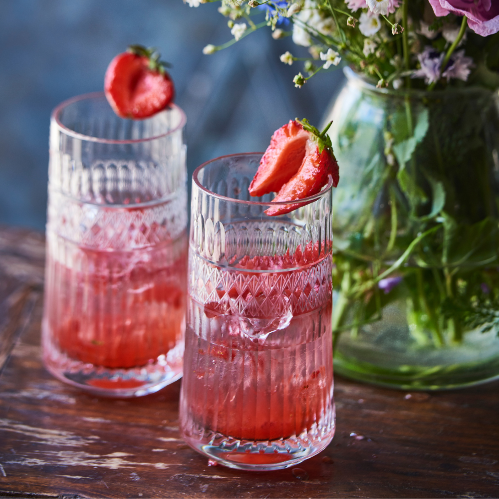 Drinken gin og tonic med jordbærsirup og jordbærpynt i rillede glas