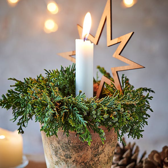 Juledekoration i lerpotte med lyskrans af cypres