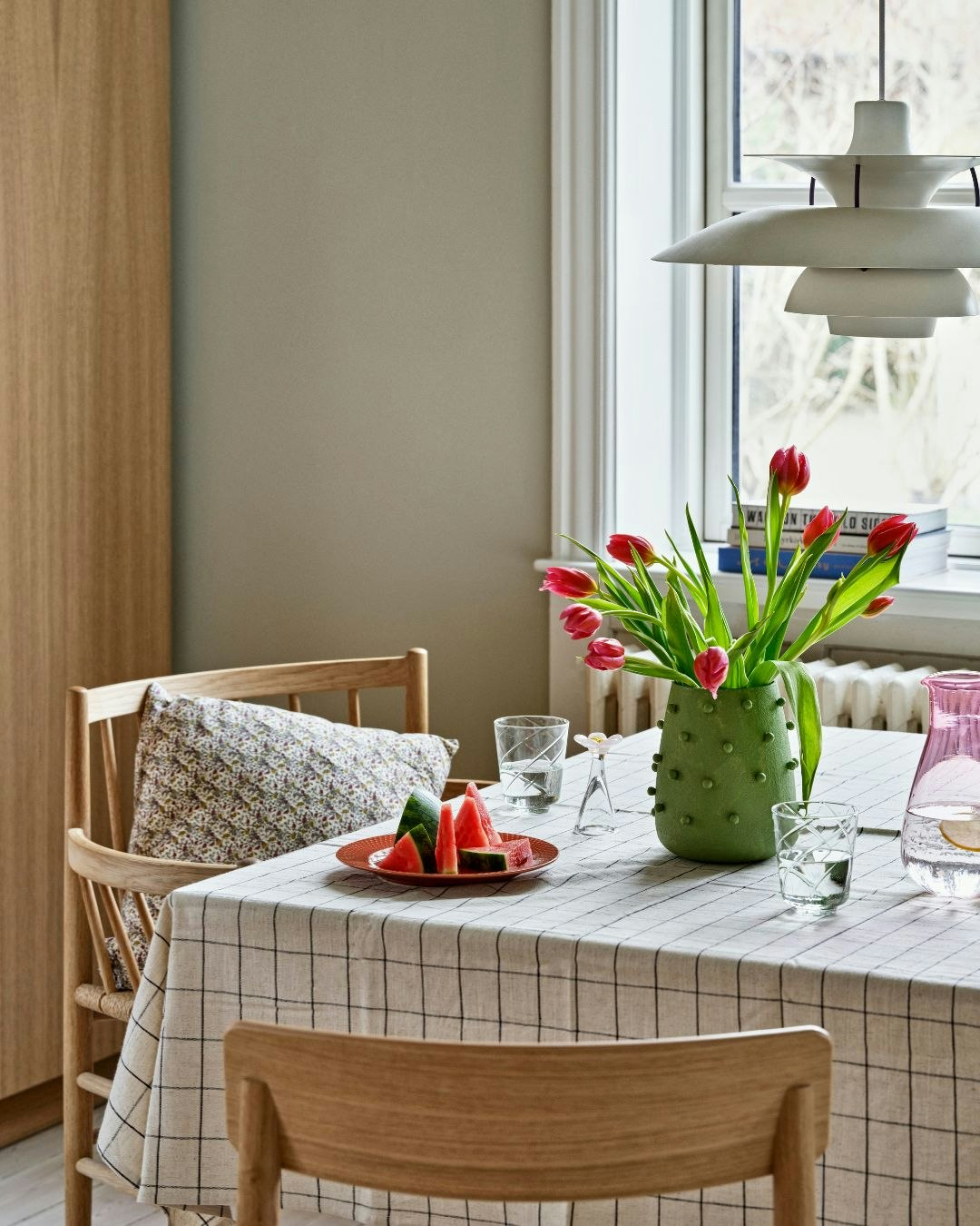 Dækket bord med dug, vandmelon og vase med tulipaner