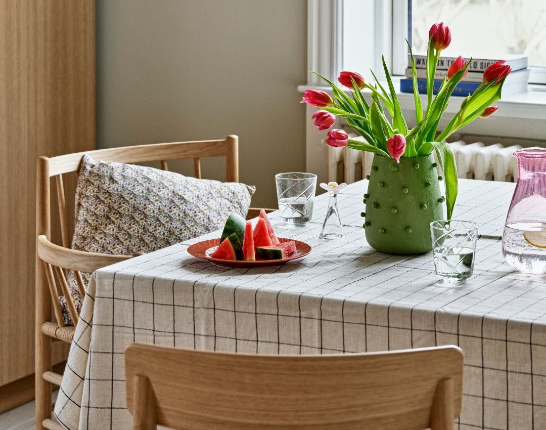 Dækket bord med dug, vandmelon og vase med tulipaner