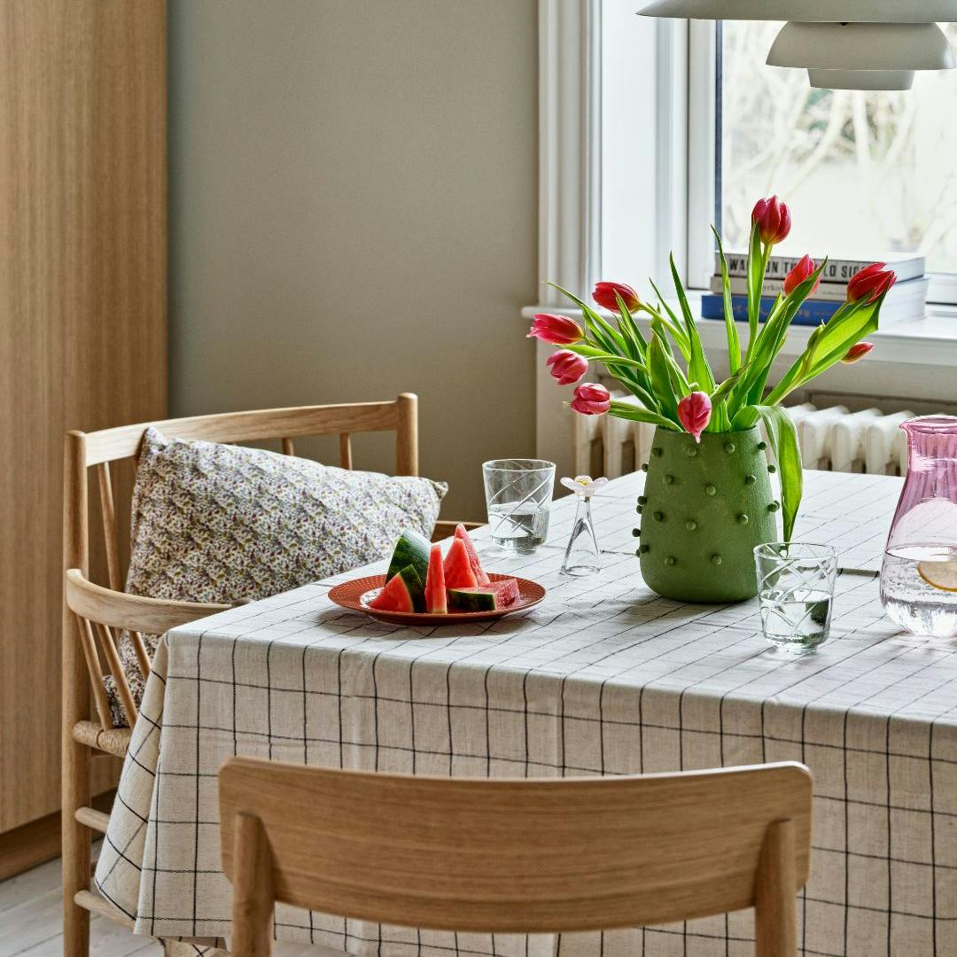 Dækket bord med dug, vandmelon og vase med tulipaner