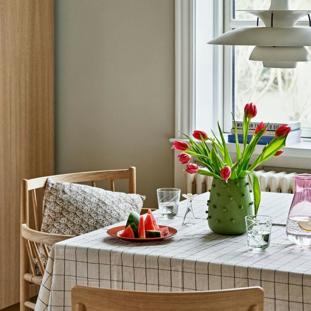 Dækket bord med dug, vandmelon og vase med tulipaner