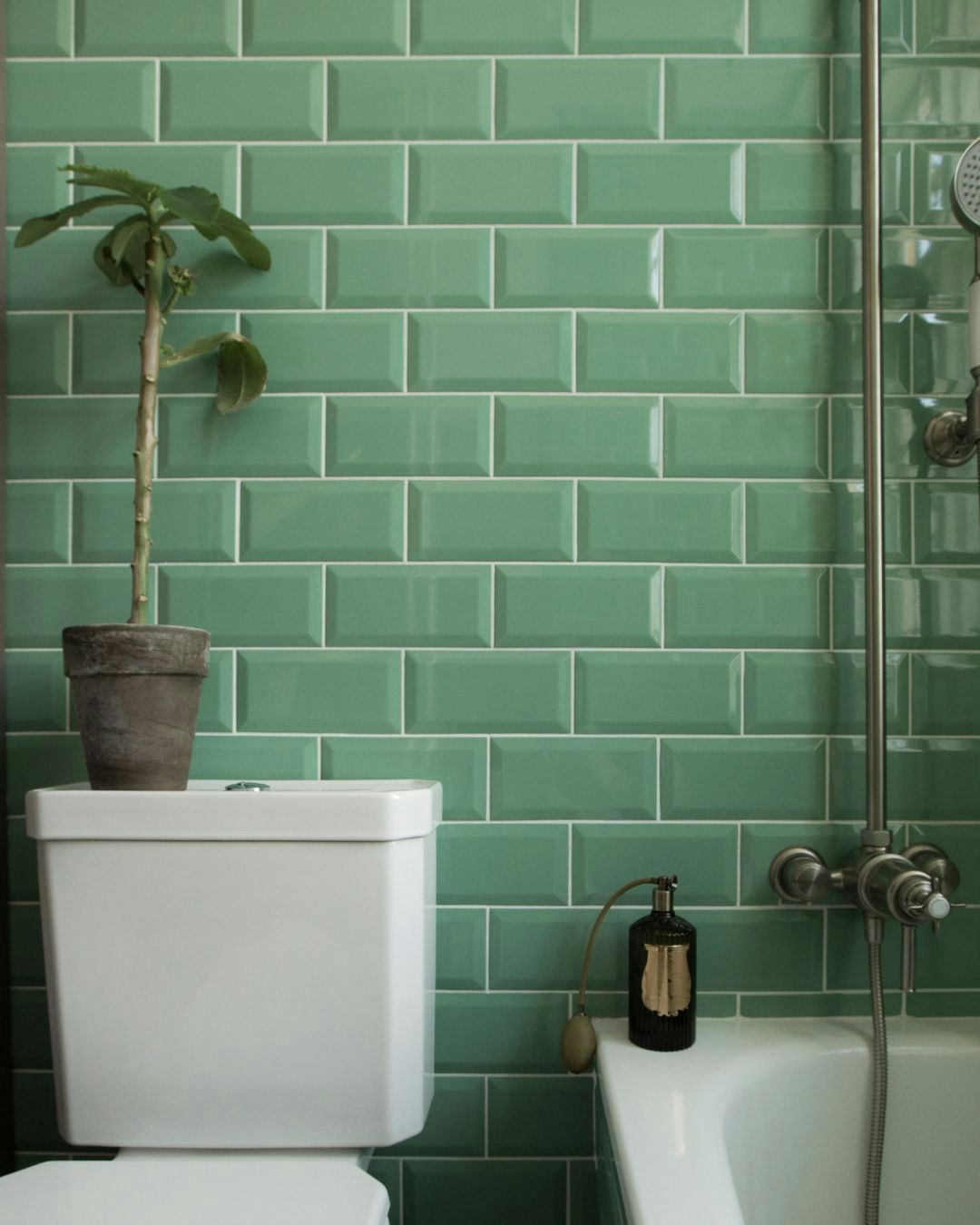 Hvidt toilet på badeværelse med grønne klinker