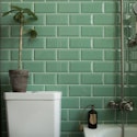 Hvidt toilet på badeværelse med grønne klinker