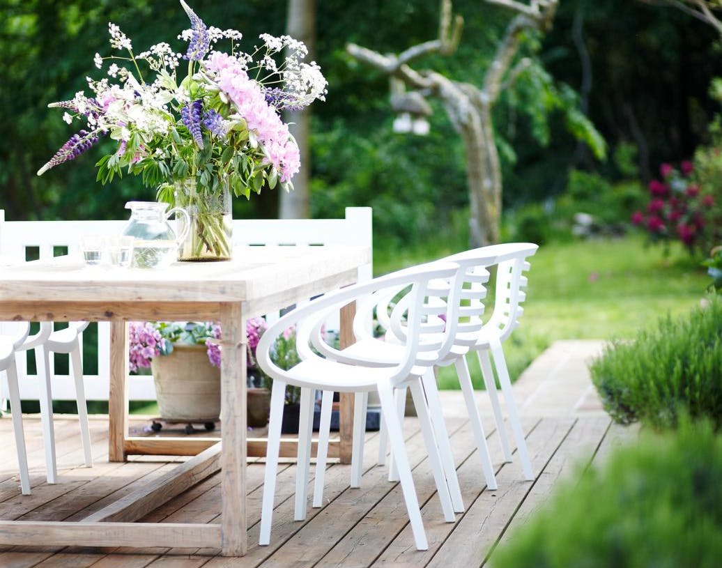 Hvide havemøbler med lyserød blomsterbuket på terrasse