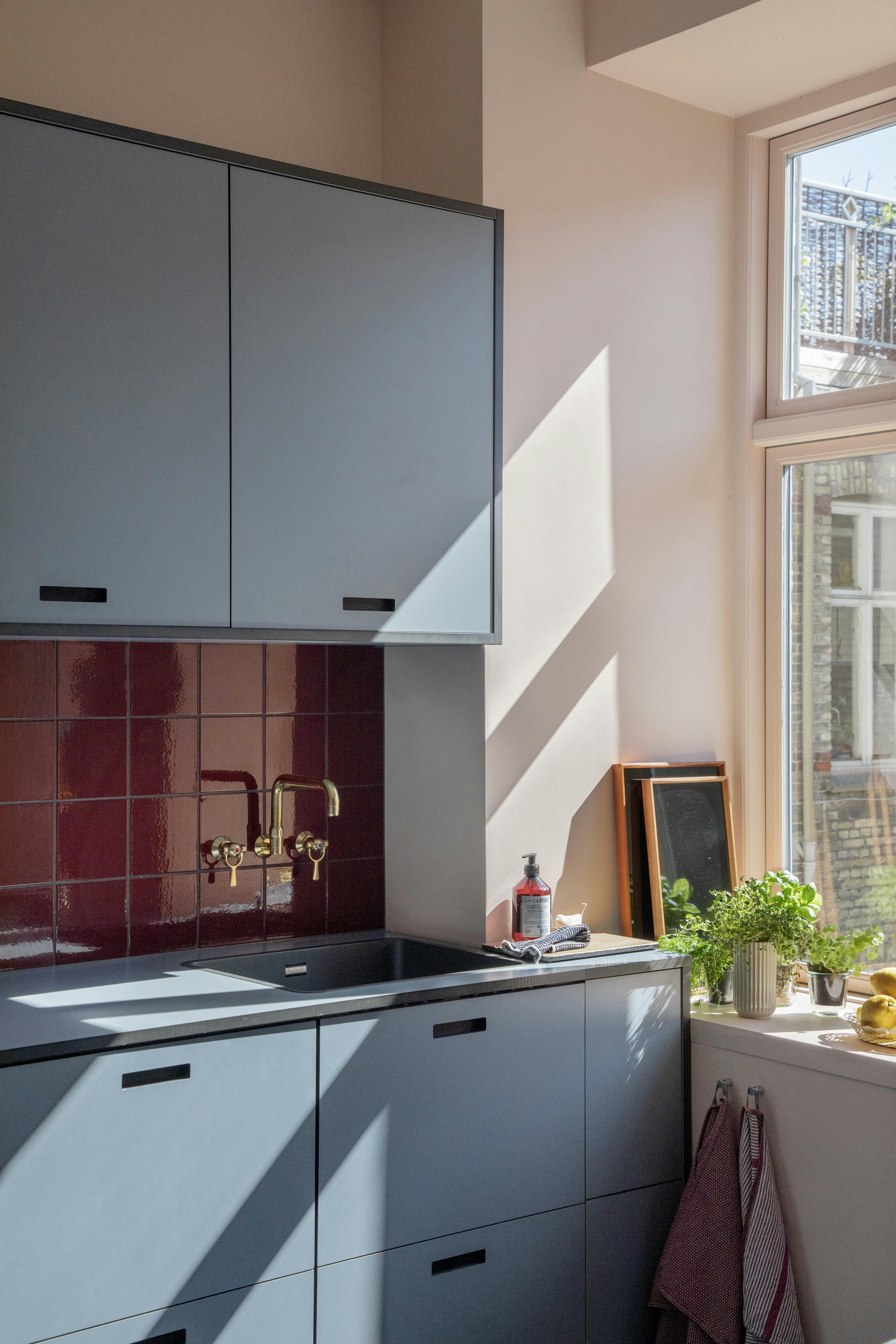 Farverigt køkken med blå fronter, røde fliser og lyserøde vægge