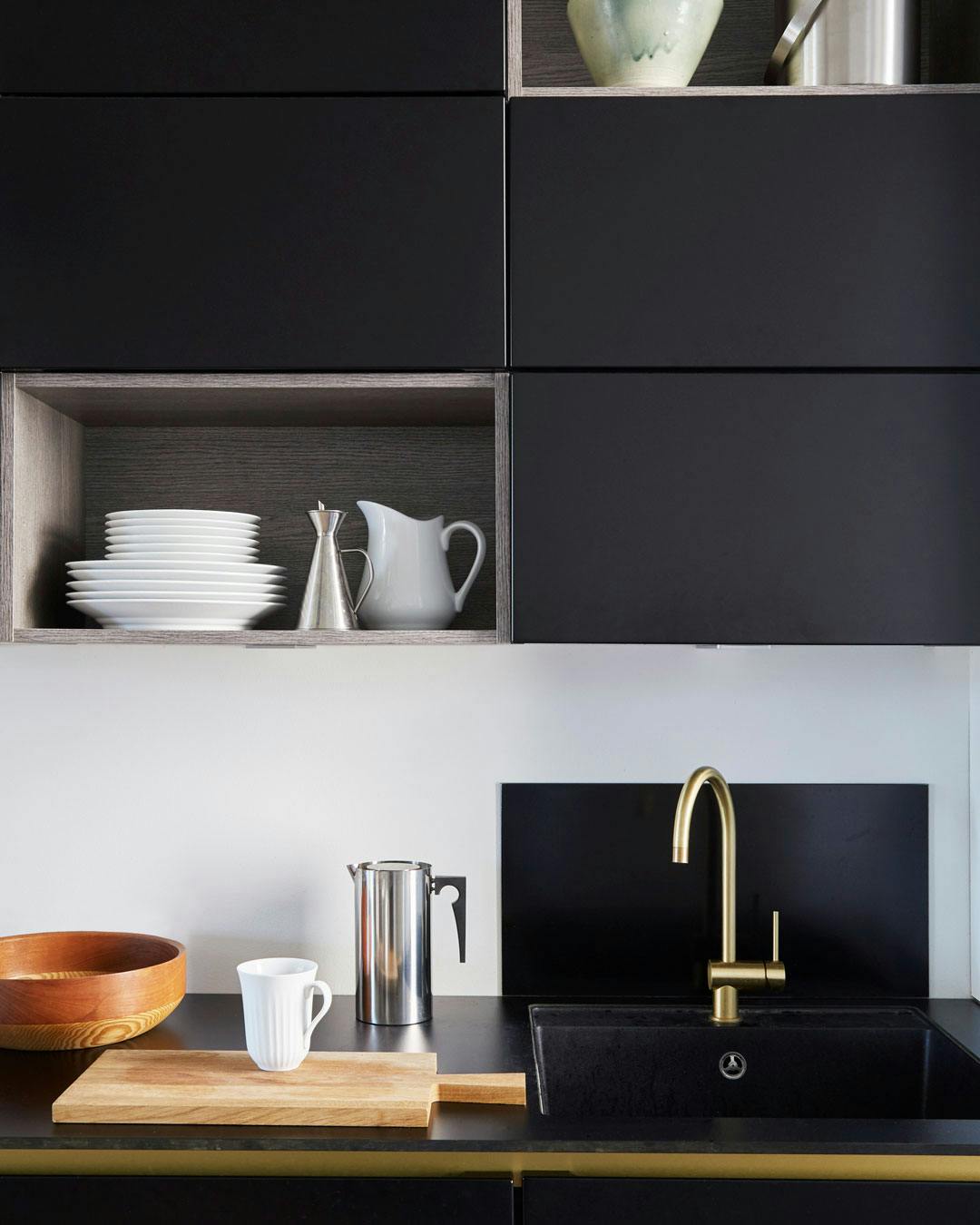 Sortlakeret køkken med messingdetaljer