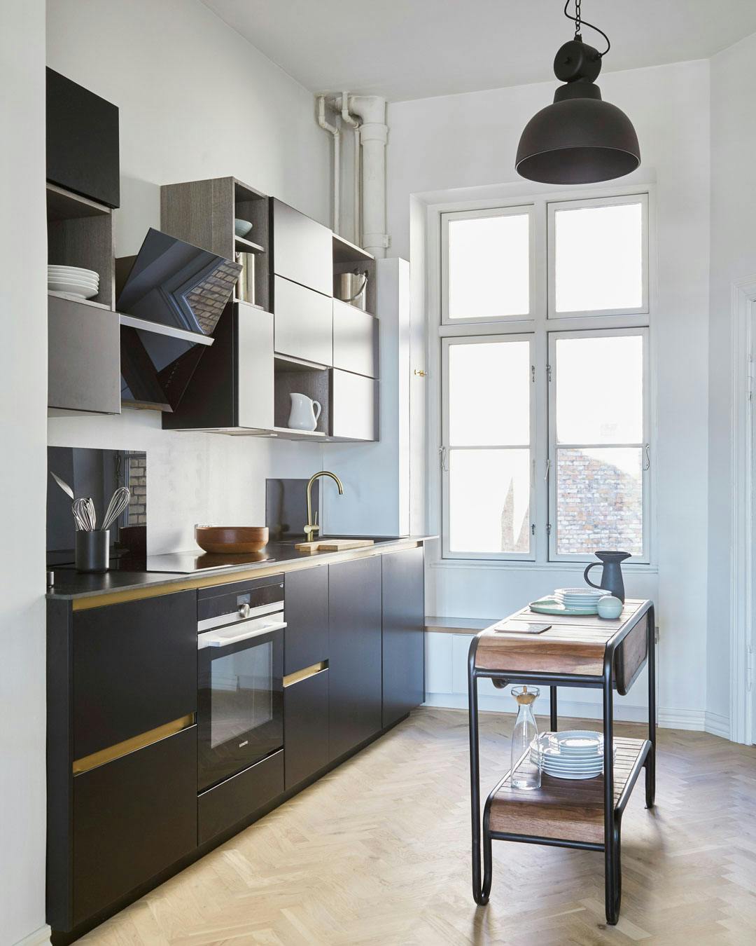 Sortlakeret køkken med messingdetaljer