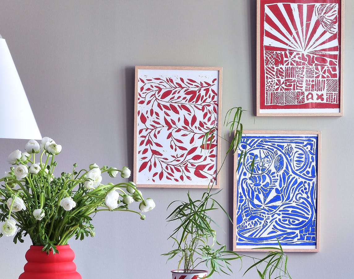 Indrammede, hjemmelavede linoleumstryk i røde og blå farver