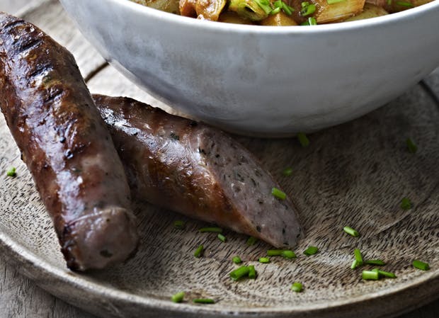 Gennemskåret stegt pølse med mørkt skind og synlige urter i kødet. 