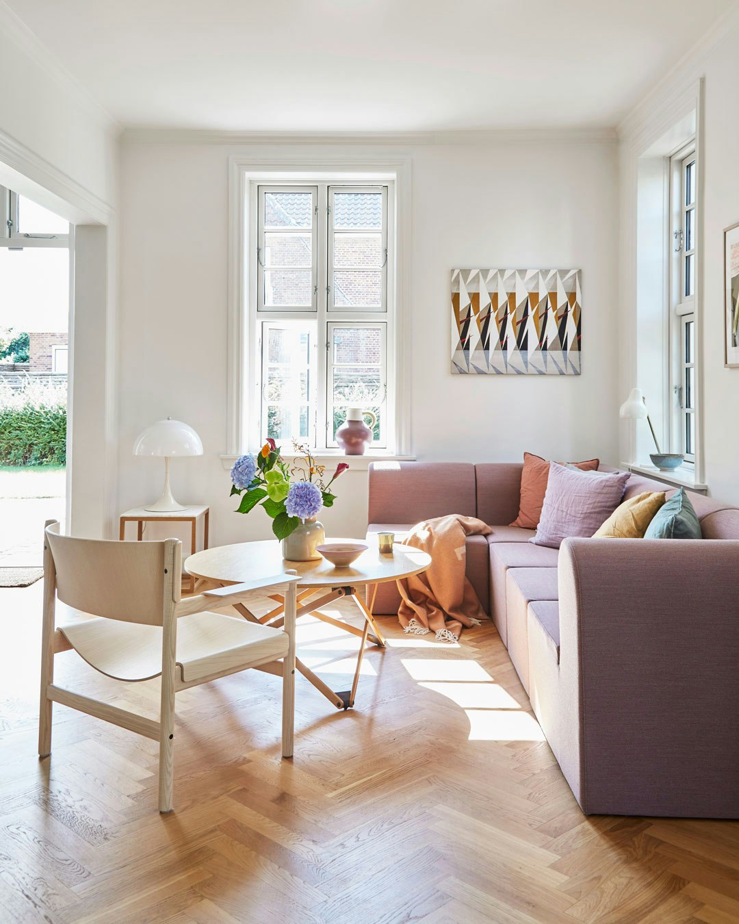 Stue med lilla sofa og sildebensparket