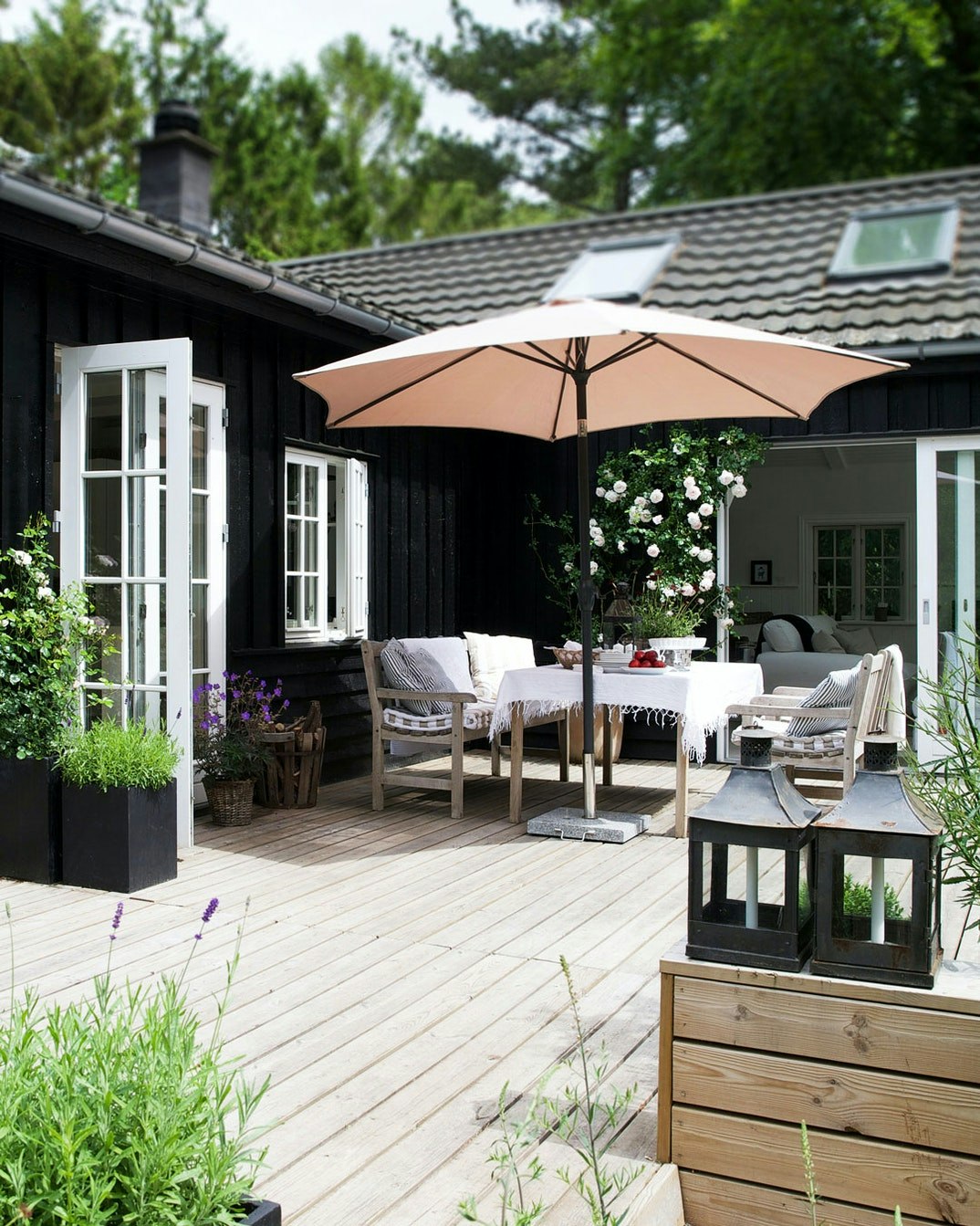 traeterrasse-med-parasol-sortmalet-sommerhus-med-hvide-vinduer