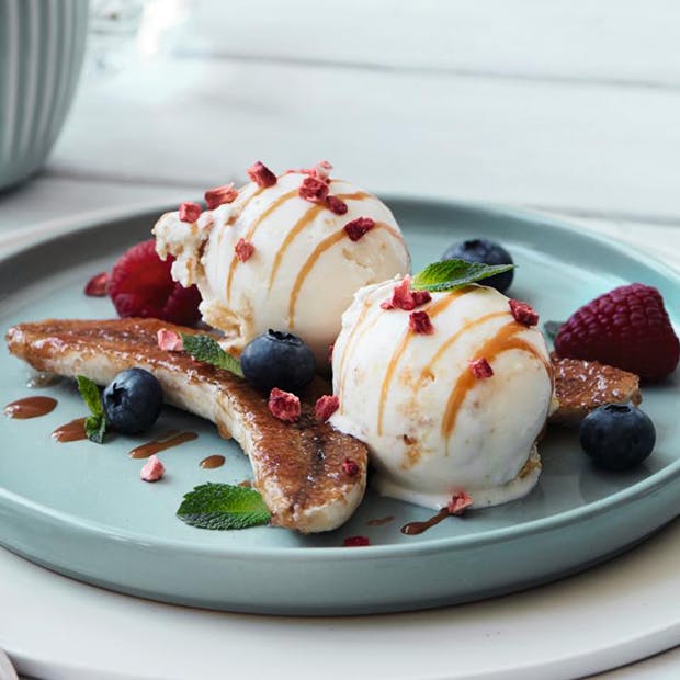 moderne bananasplit med karameliserede bananer og is med smag af cheesecake og passionsfrugt