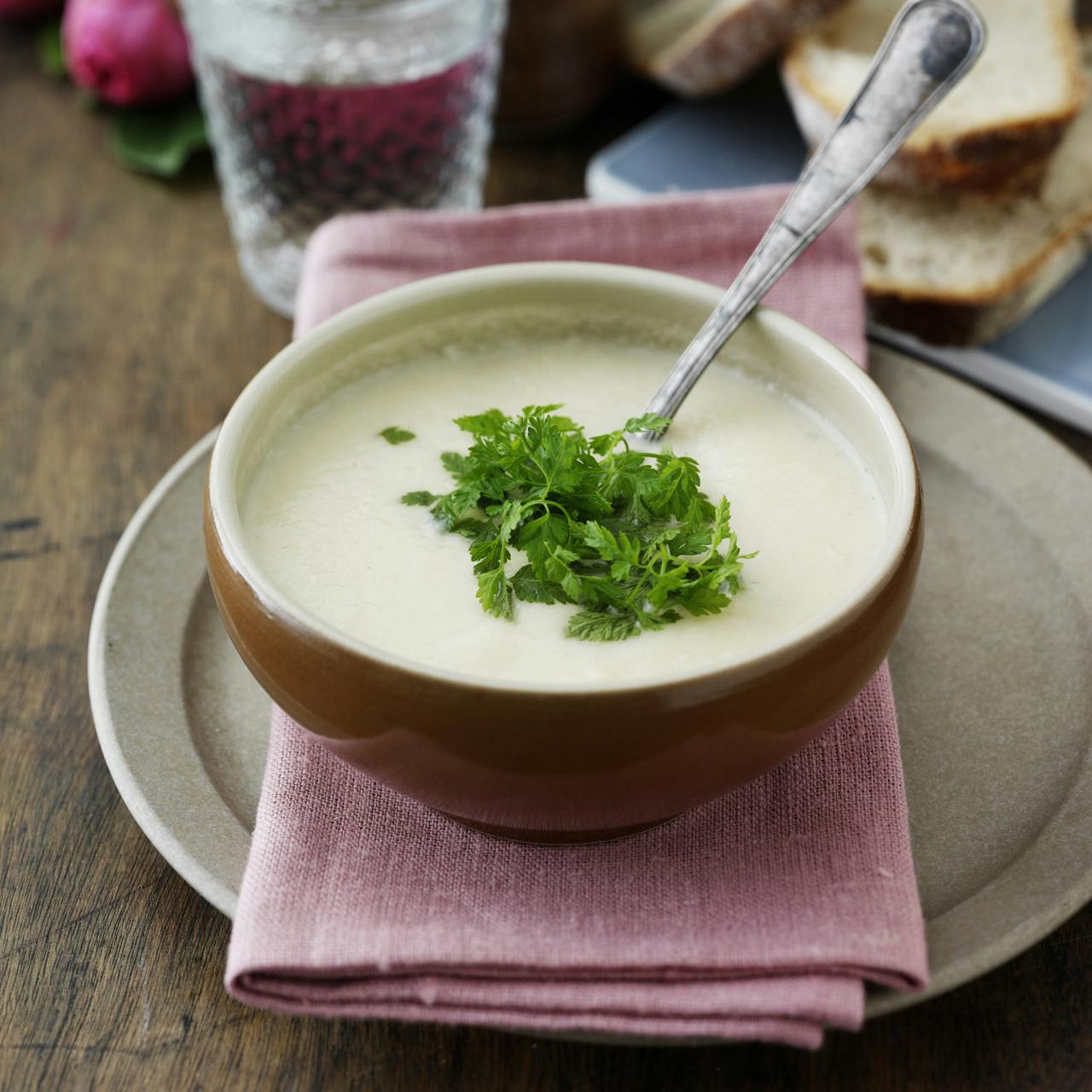 Blomkålssuppe serveret med lidt kørvel på toppen og et godt brød