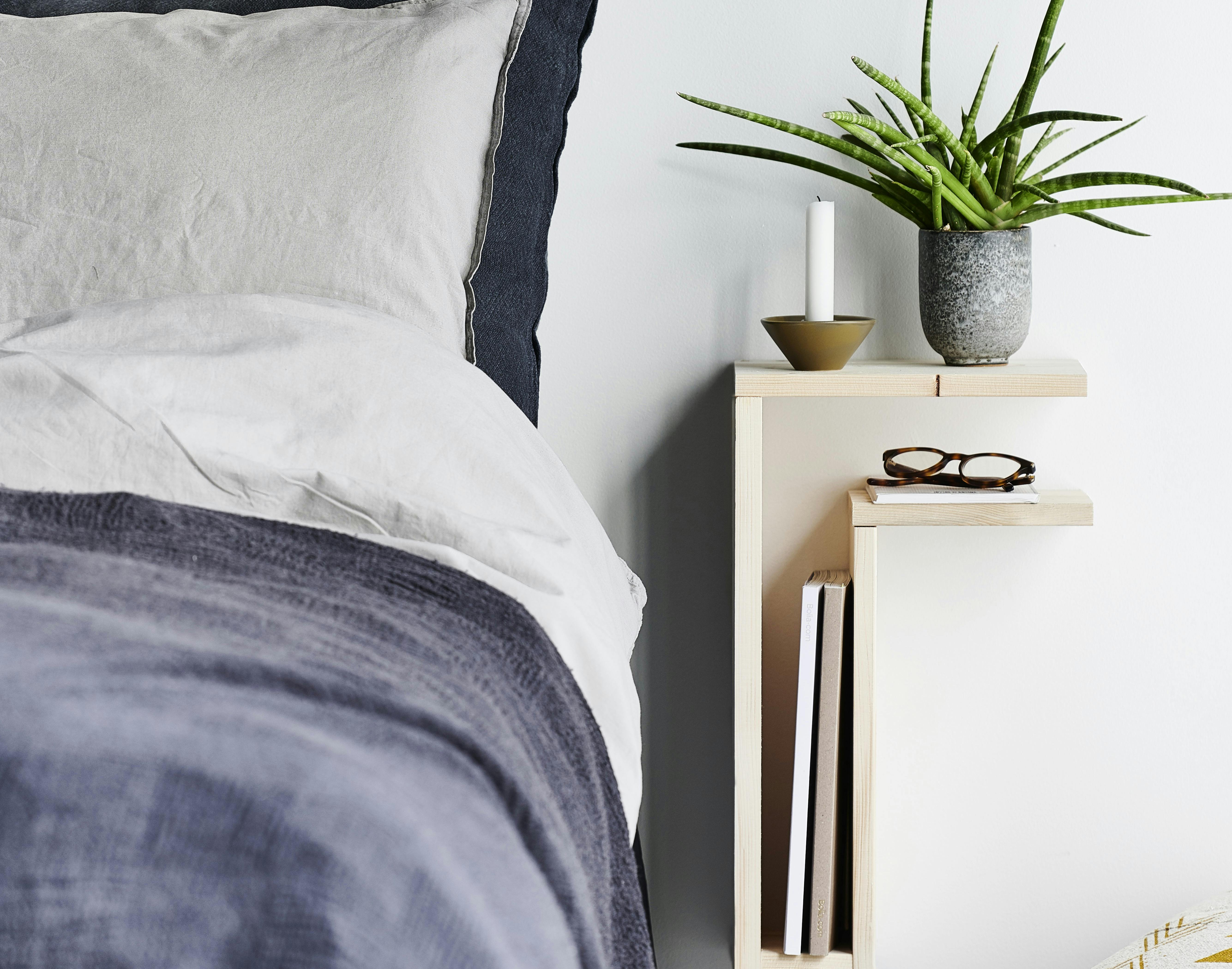 Væghængt sengebord med en grøn plante på og plads til opbevaring