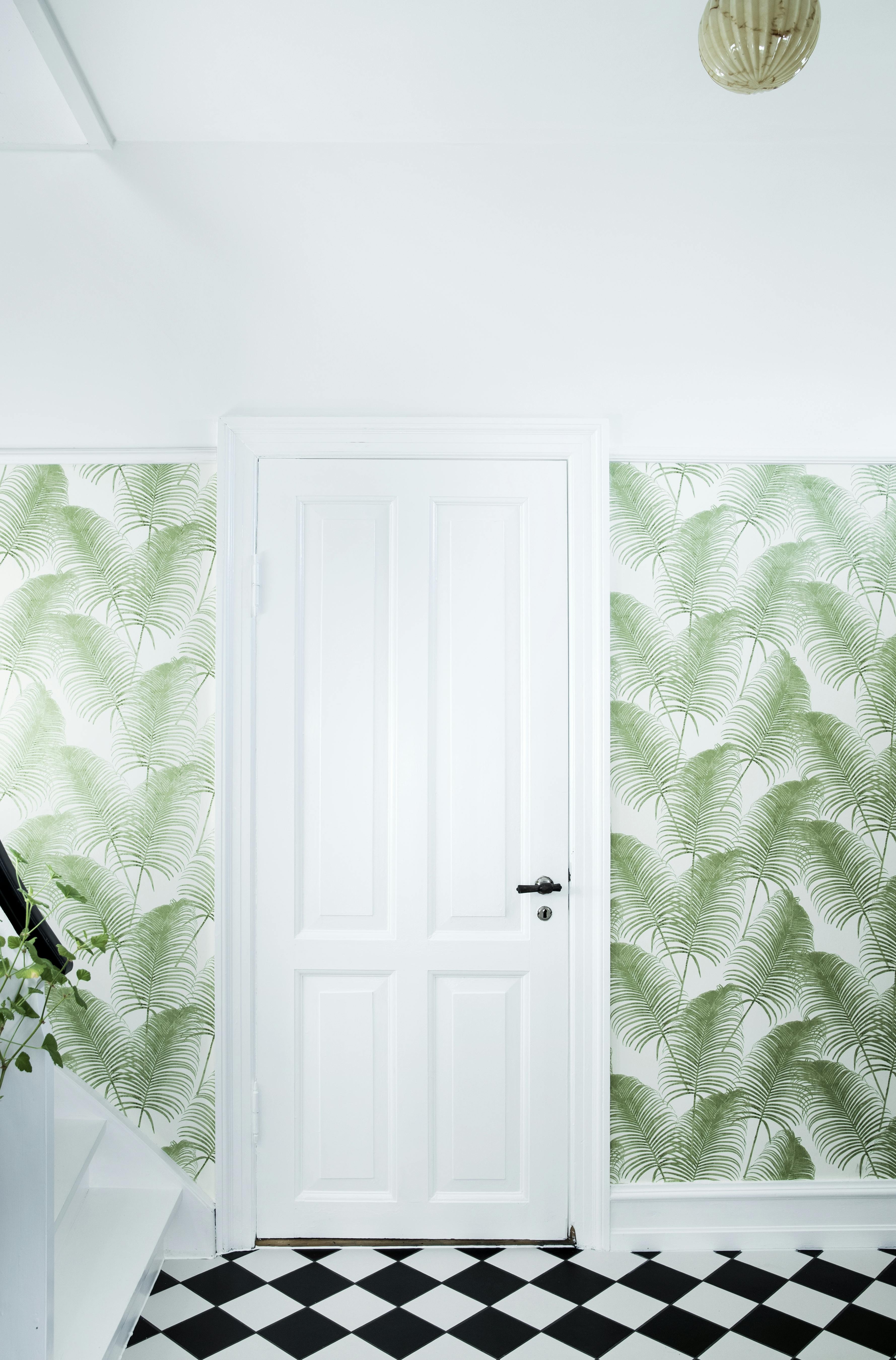 Mønstret, grønt tapet rundt om en hvid dør