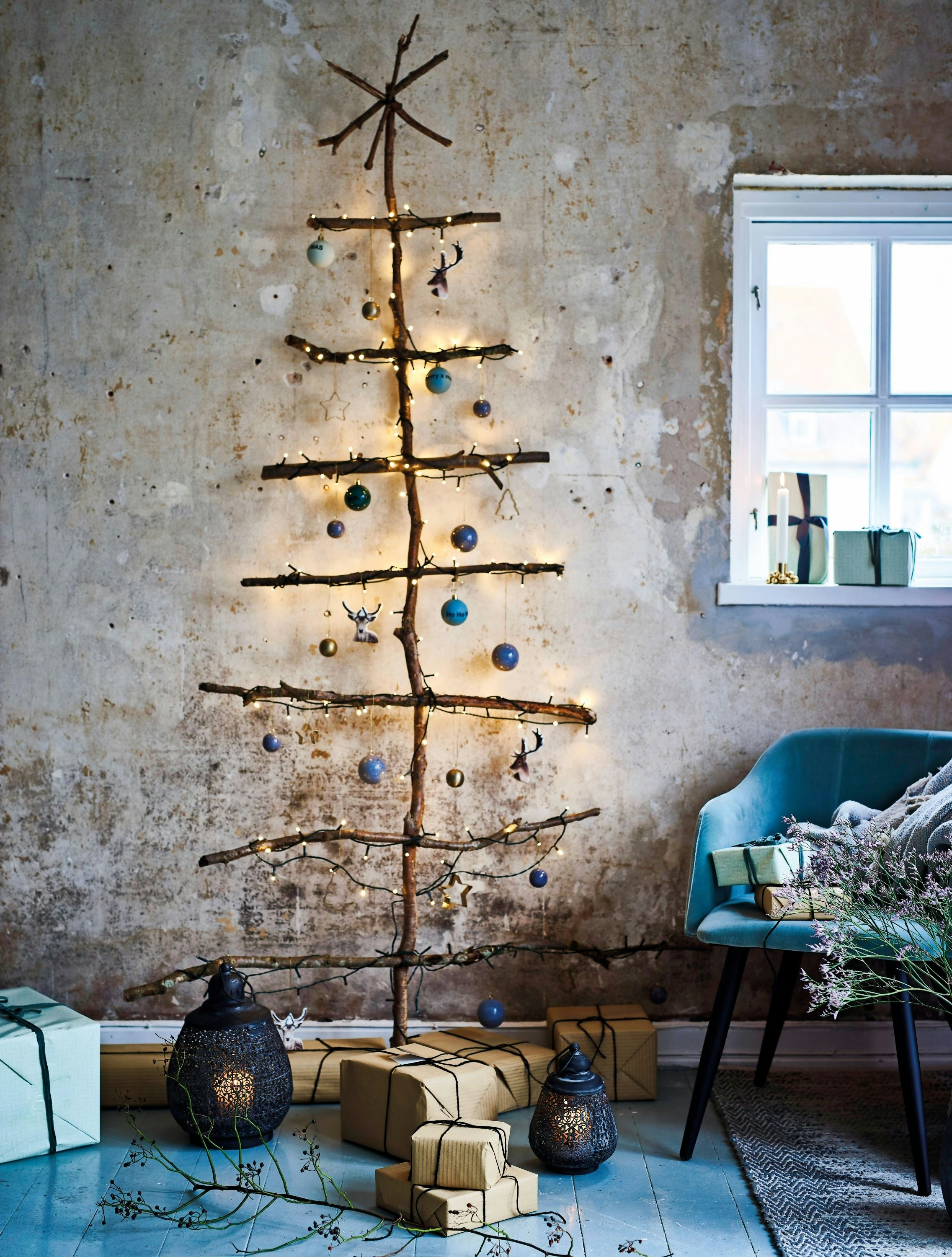 Vægjuletræ af grene med lys og julepynt