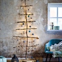 Vægjuletræ af grene med lys og julepynt